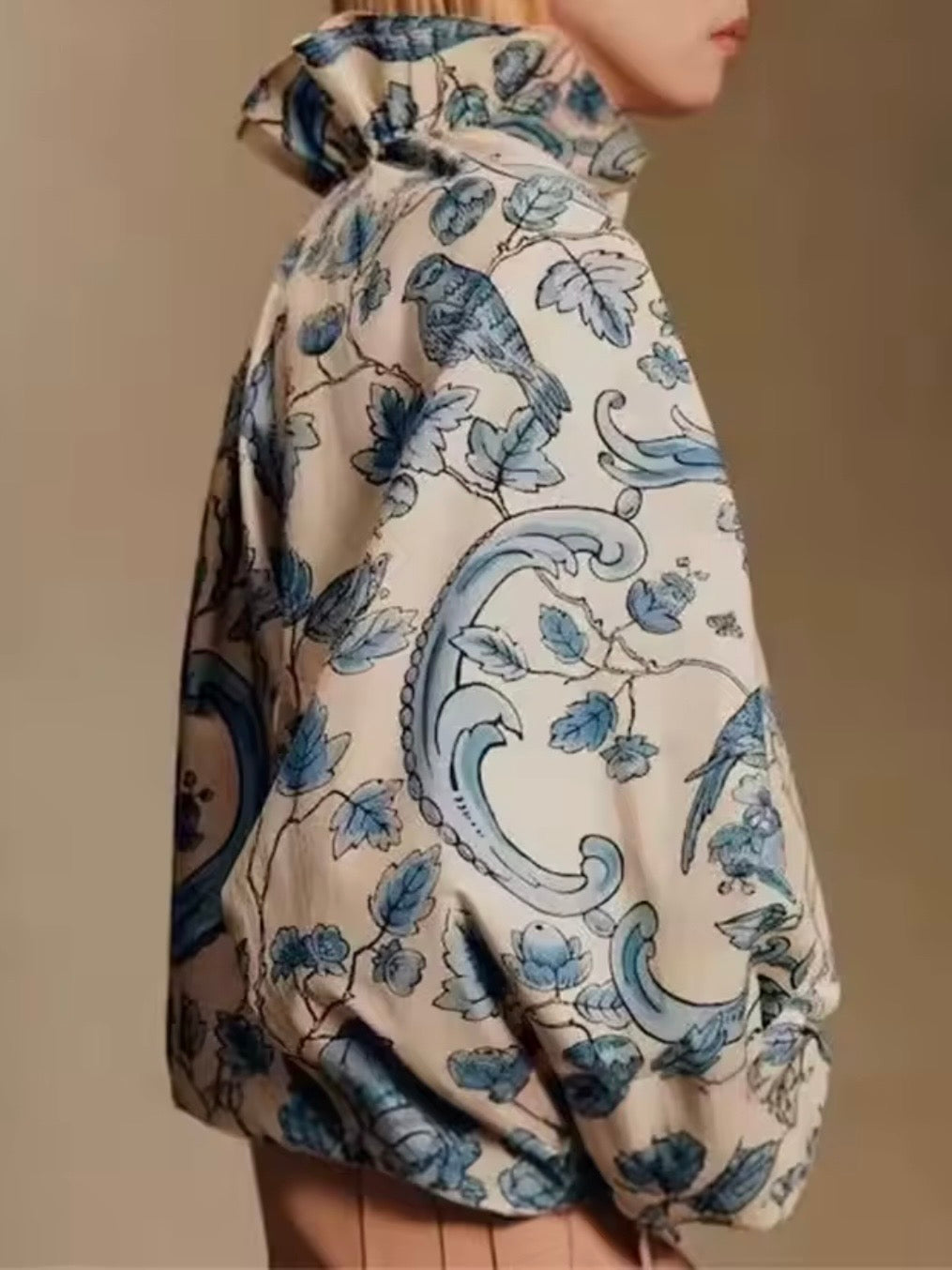 Camisa de cuello alto con estampado floral en color beige y azul claro y detalles de volantes