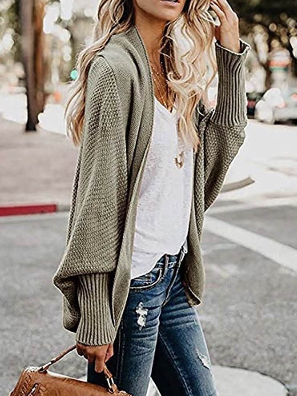 Model wears an open-front cardigan with button details, a cable knit design, ribbed cuffs and hem.